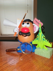 Mister Potato Head holding office objects and toys